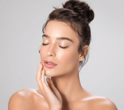Woman with lip fillers closing her eyes and touching her face.