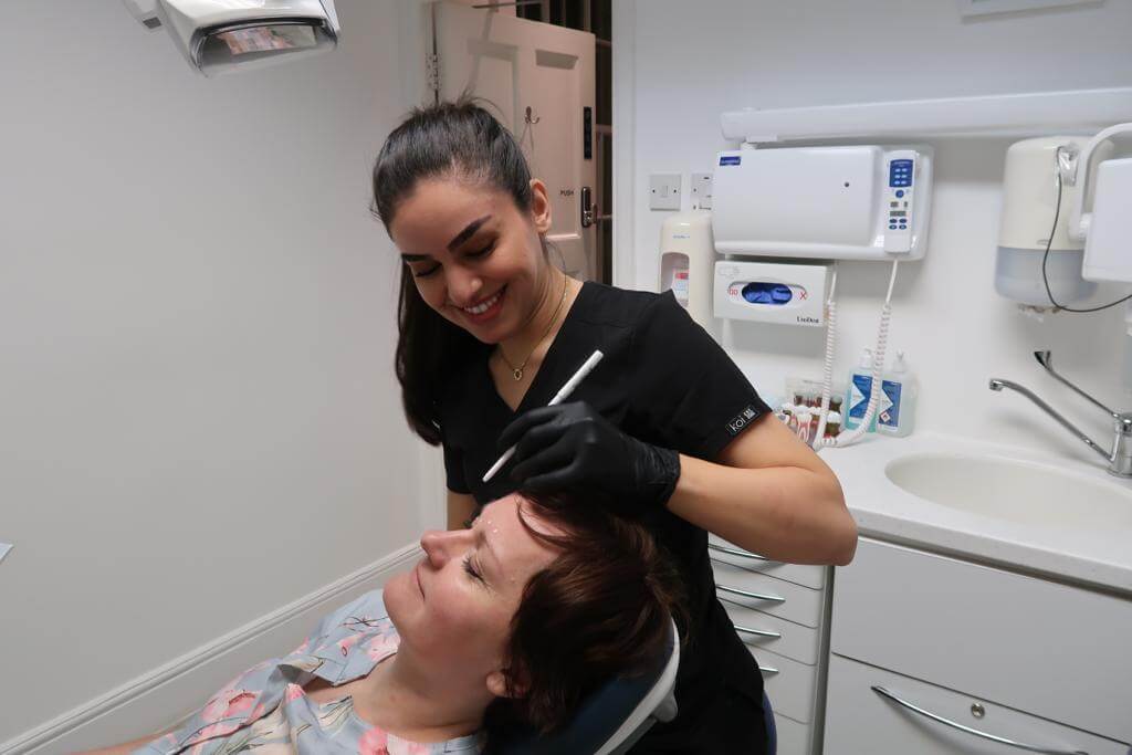 Woman preparing a facial treatment on a patient.